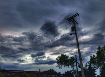 Low angle view of electricity pylon against cloudy sky