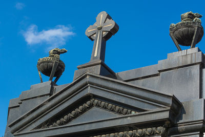 Low angle view of bird perching on statue against blue sky