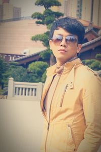 Portrait of man wearing sunglasses standing against building in city