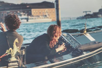 Rear view of people sitting on boat in sea