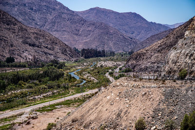 Dirt road amidst landscape and mountains against sky