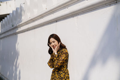 Woman smiling while standing against wall