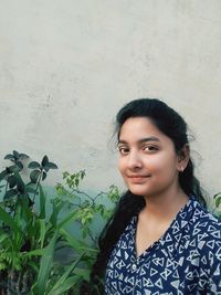 Portrait of smiling young woman standing against plants