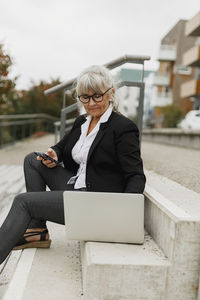 Senior woman using laptop on stairs