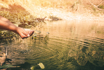 Midsection of man touching water in lake