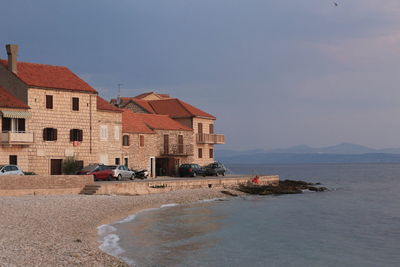 Houses on beach by buildings against sky