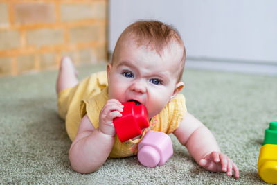 Little caucasian girl playing with soft plastic constructor at home.