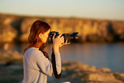 Side view of woman photographing outdoors