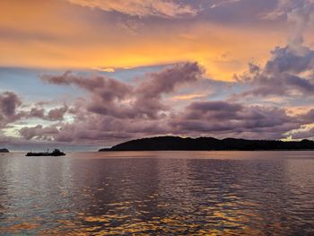 Scenic view of sea against dramatic sky during sunset