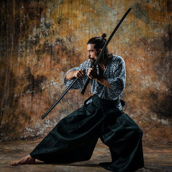 Full length of man practicing ninja against wall