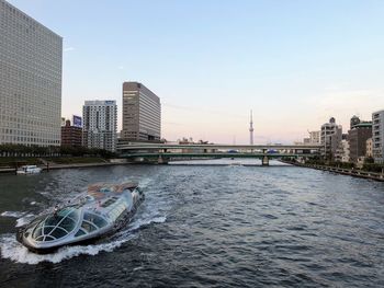 Bridge over river by buildings against sky in city