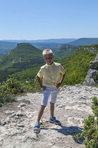 Full length of boy standing on mountain against sky