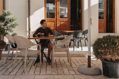 Rear view of woman sitting in front of house