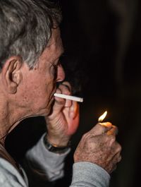 Side view of man igniting cigarette with lighter