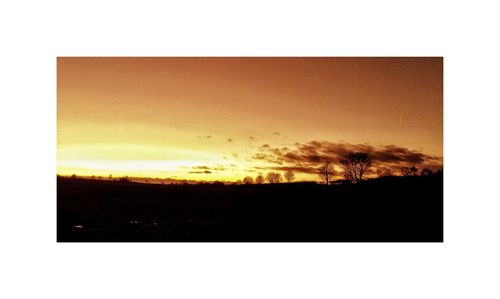 Silhouette field against sky during sunset