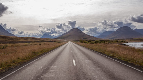 Road leading towards mountains against sky