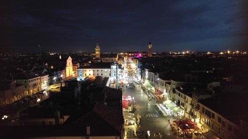 High angle view of illuminated road amidst buildings against sky at night