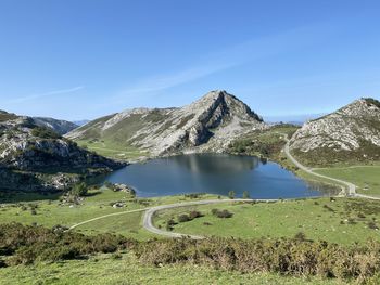 Scenic view of lake and mountains against clear blue sky