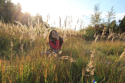 Woman sitting on field against sky