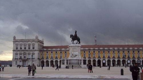 Statue in town square against cloudy sky