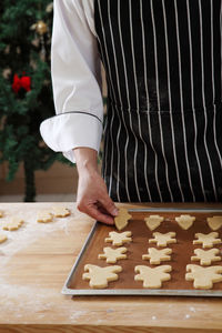 Midsection of chef preparing gingerbread cookies on table at kitchen