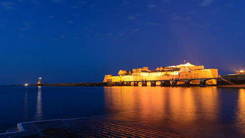 Illuminated building by sea at night