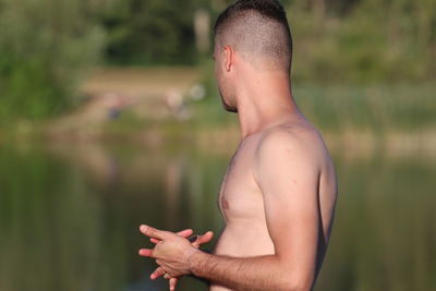 Side view of shirtless man standing outdoors