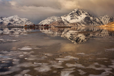 Scenic view of lake by snowcapped mountains against sky during winter