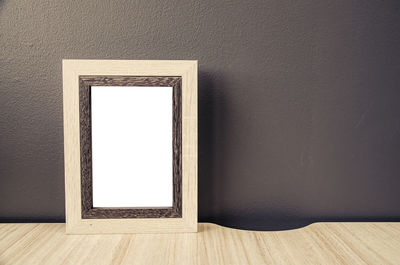 Close-up of blank picture frame against wall at home