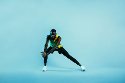 Man exercising against blue background