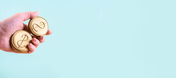 Close-up of hand holding ring over white background