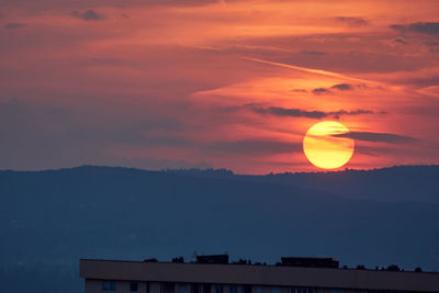 Scenic view of silhouette mountains against romantic sky at sunset