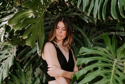 Beautiful young woman standing against plants