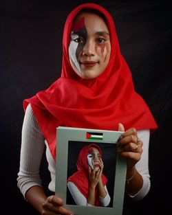 Portrait of smiling mid adult woman against black background