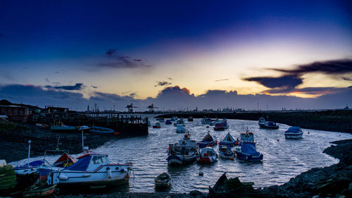 Boats moored at harbor against sky during sunset