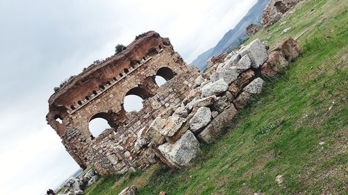 Low angle view of old ruin building against cloudy sky