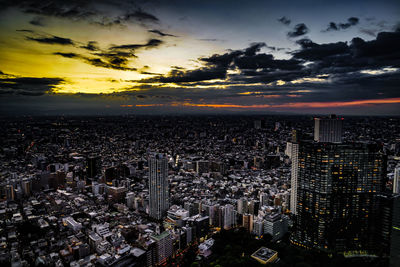 Aerial view of illuminated cityscape against sky during sunset