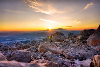 Rocks on landscape against sky during sunset