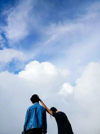 Rear view of men standing against sky