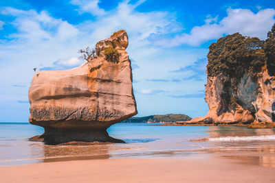 Rock formation on beach against sky