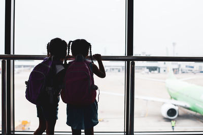 Rear view of siblings standing at airport