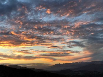 Scenic view of mountains against cloudy sky during sunset