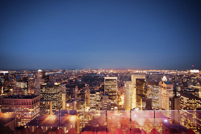 Illuminated cityscape against clear sky at night