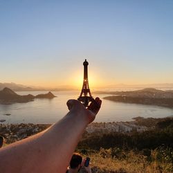 Person holding umbrella against sky during sunset