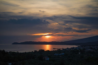 Scenic view of sea against dramatic sky during sunset