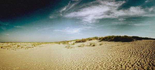 Scenic view of beach against cloudy sky