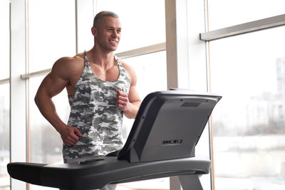 Smiling man exercising on treadmill at gym