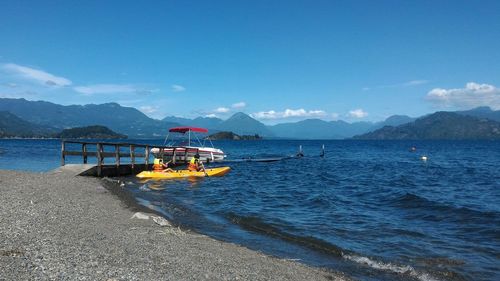 Children canoeing in lake against sky