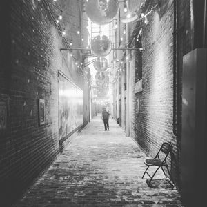 Rear view of man walking on footpath amidst buildings