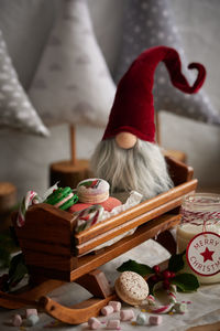 Santa claus decoration in sled on table with christmas macarons and milk jar